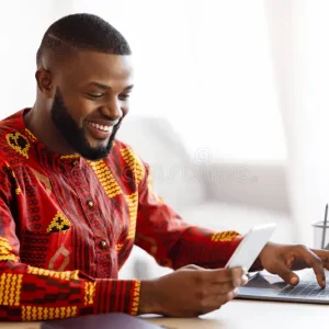 cheerful-black-man-traditional-african-clothes-using-smartphone-laptop-cheerful-black-man-traditional-african-clothes-389803045 cheerful-black-man-traditional-african-clothes-using-smartphone-laptop-cheerful-black-man-traditional-african-clothes-389803045